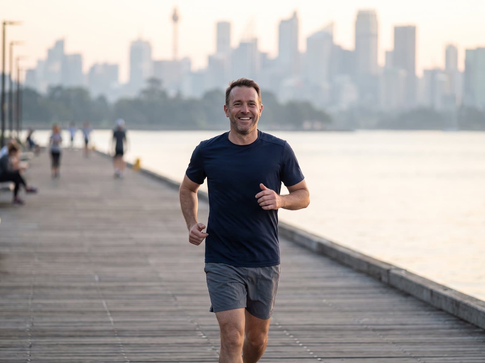 A man jogging along a waterfront boardwalk at sunrise