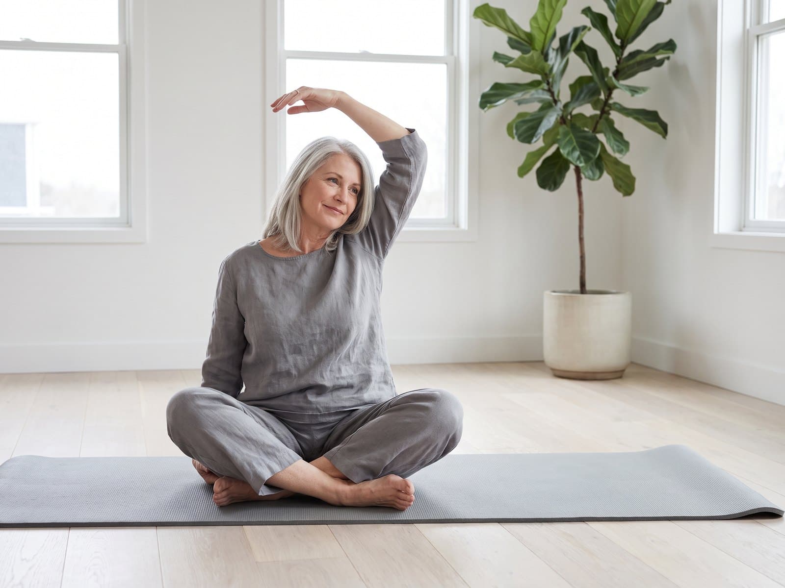 A woman stretching on a yoga mat in a bright living room